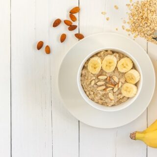 Top view of Bowl of oat flakes with sliced banana close-up on wooden table.