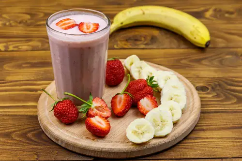 Glass of fresh smoothie of strawberry and banana on a wooden table